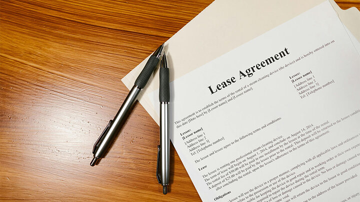 A lease agreement form, on a table with two writing pens.